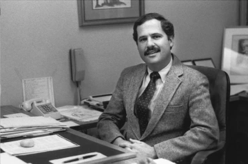 Portrait of Paul Marcus seated at his desk.
